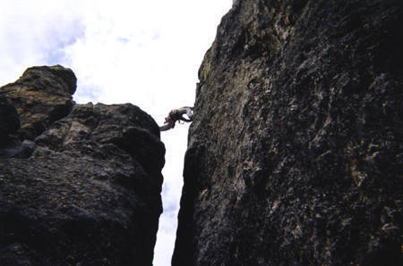 Here's a picture of the infamous "step-across."  This is my first time up Spire 4; on lead, no less.  I'm a tall, spindly freak, so I could spend all day between the two summits, but short people usually have to think for a few moments before their "leap of faith."  This picture is a change from the traditional "butt shot," since this is actually a "crotch shot."  :-)