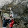 Greg took this picture.  My brother, Rob, and <br>
Nathan Renner are spotting.  You can see <br>
from this photo that I didn't use the "hidden" <br>
undercling.  From the "under the roof" crimp <br>
(left hand), I went right to the first roof crimp <br>
then bumped to the second (right hand).  I <br>
heel-hooked out left in a shallow scoop; <br>
moved my left hand to the first roof crimp <br>
then gunned for the top.  This is such a good <br>
route.