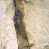 At the hidden crux wondering how secure the holds are in the flare above the bulge. Photo by Gabe C.   