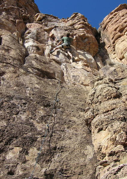 Climber at the crux bulge near the top of the route.