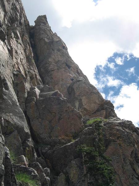 A party is visible on the 2nd pitch.  The first pitch begins below the obvious tree and goes up the left corner system to the top of the huge big block.  A dirty, walkable ledge system takes you to the base of the tower where the climber in blue is just barely visible.  Gain this tower by climbing the left corner, until it is possible to traverse out right onto the block and face climb to its top.