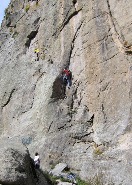 Climber starting the crux section of the first pitch.  There is a 2-bolt anchor on the ledge to the climber's left.