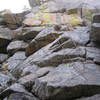 Sword In The Stone.  Climb up and left past several small overhangs to the arete. Climb up the knife edge arete and pass a final bulge to the anchor.