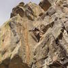 Trying to figure out the complicated first crux. The goal is to get into a higher stem with the right foot on the arete above the bulge on the right wall.<br>
<br>
Photo by Paul Rezucha.