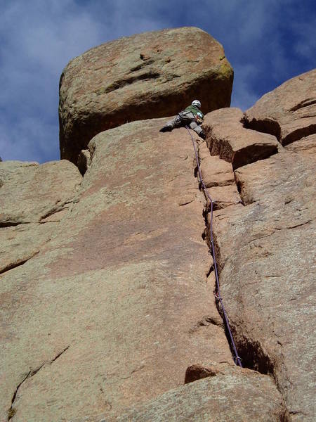 On the final moves. The climb exits right around the huge block to a belay amongst huge boulders.