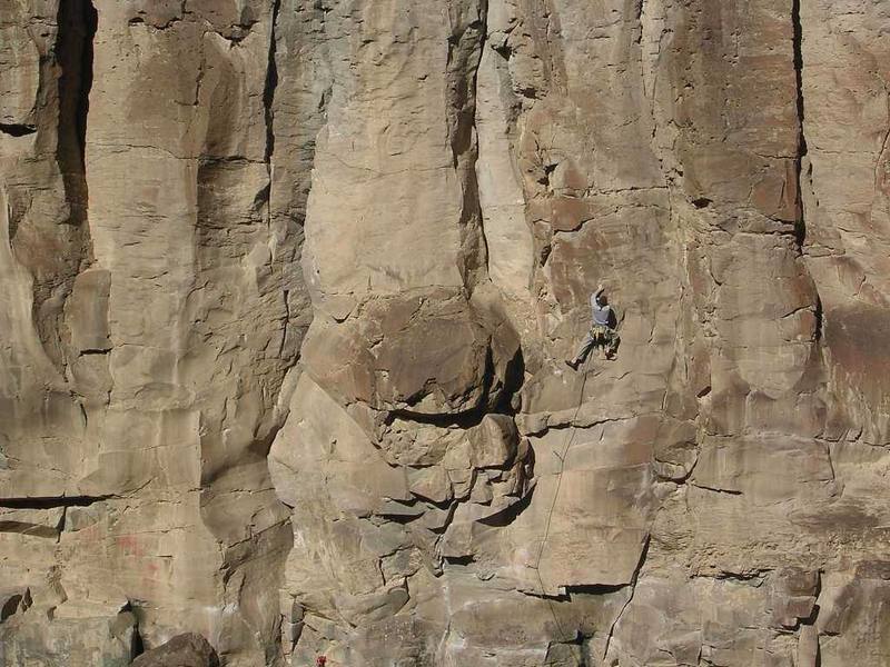 The route follows the arete forming the left-facing corner to the right of this climber. Start under a small roof with Fixe hangers on your right.