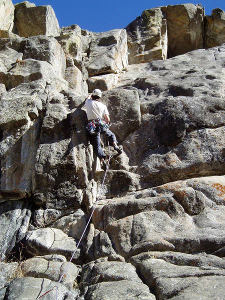 Greg has a crummy hold with his left hand. A jug awaits after standing on the arete. Greg ended up skipping the last bolt.