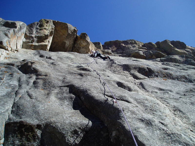 Greg's on the crux at the second to last bolt. The route climbs right to the left edge of the quartz dike at the bottom of the photo and then moves left on big humps between the 2nd and 3rd visible bolts. At the bolt with the long sling it moves back right past another closely spaced bolt to the quartz band and up that to the anchors.