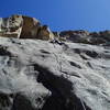 Greg's on the crux at the second to last bolt. The route climbs right to the left edge of the quartz dike at the bottom of the photo and then moves left on big humps between the 2nd and 3rd visible bolts. At the bolt with the long sling it moves back right past another closely spaced bolt to the quartz band and up that to the anchors.