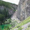 <br>
Grassi is a great place to escape summer heat waves. The trail from the dam down to Grassi Lakes is in the gully, center. The belay platforms for Meathooks can be seen in the shady alcove right of the lake.          <br>
<br>
One problem unique to Grassi is the occasional rockfall.  The Spray Lakes road is just above the meathooks wall and non-climbers will sometimes toss rocks.  