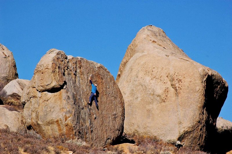 Unknown climber on an unnamed v0 on the southeast face of the Sunshine Boulder.  The massive Drifter Boulder is just behind it to the right.