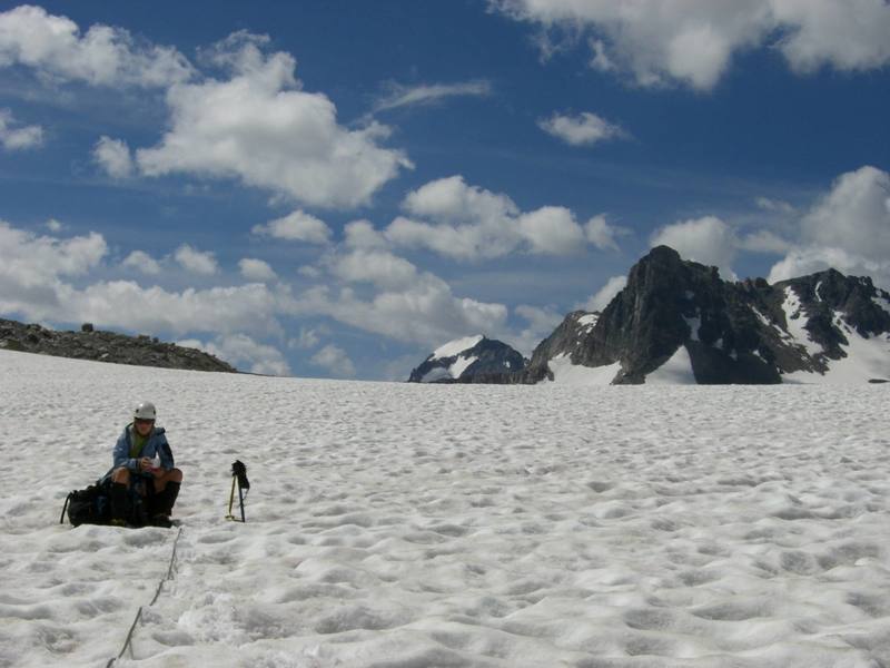 Sara snacking on the Continental Glacier, looking south to Turret Peak and Gannett Peak