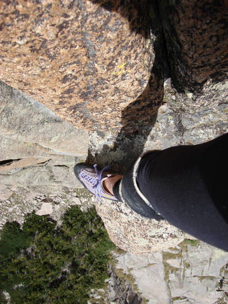 View down from the alternative belay stance, 140 feet above Ledge 1. This 12-inch ledge is just a few feet above the awesome overhanging chimney on pitch 2. Note the knee pad(s). Good idea.