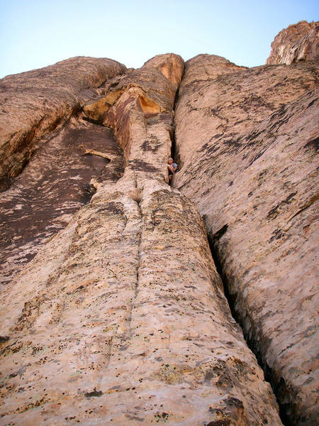 Andrew at pitch 5 belay with wide cracks stretching above.