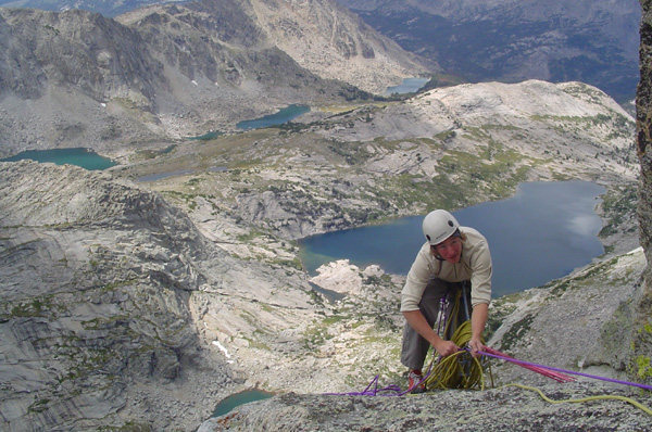 Joe on belay, with deep lake directly behind him