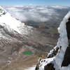 Looking down at the jade green crater lake between the Illinizas as seen from just below the summit of Illiniza Norte. Chimborazo can be seen on the horizon in the distance.