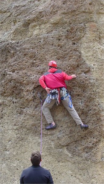 Reaching for a draw to clip the second and crux bolt of the route.  (Note that even with the first bolt clipped a grounder is possible if the belayer is unattentive.)