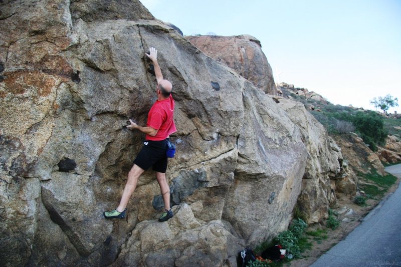 Reaching up at the start of the crux on Masterlock, V3