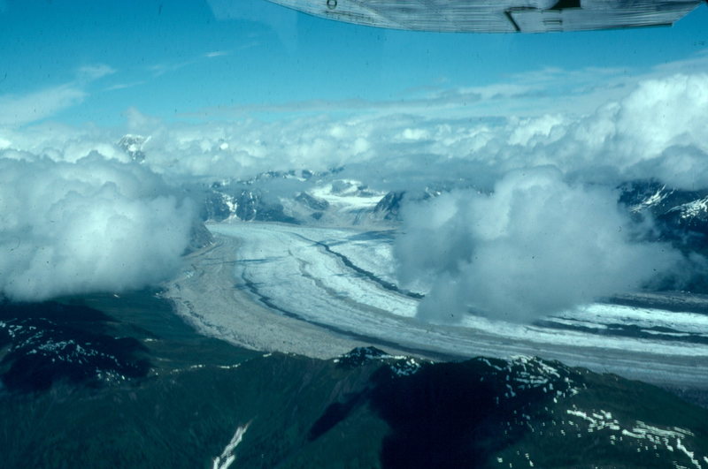 Alaska glacier, flying into Denali basecamp from Talkeetna. Colored ribbons of rock on the glacier indicate merging of several glaciers upstream.  