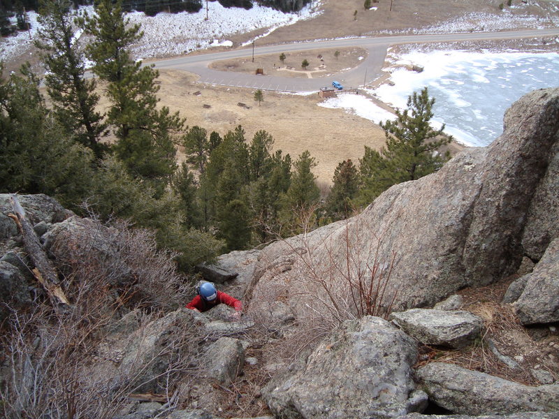 Mike making the crux move through dirty gully below the route.  You can see the parking lot for this climb below.  CO-46 is the road.