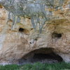 front of cave. 10 to 15 ft from ground to top of "mouth". A route coming out of the back of this cave could have around 50ft of climbing