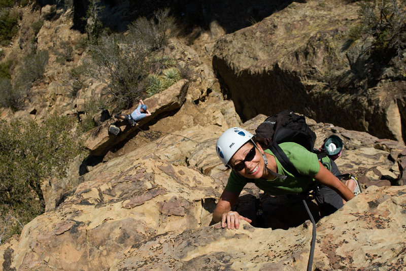 Francine Beattie climbs Rational Expectations, at the Fortress, as Audrey Walzer relaxes on "lunch ledge."