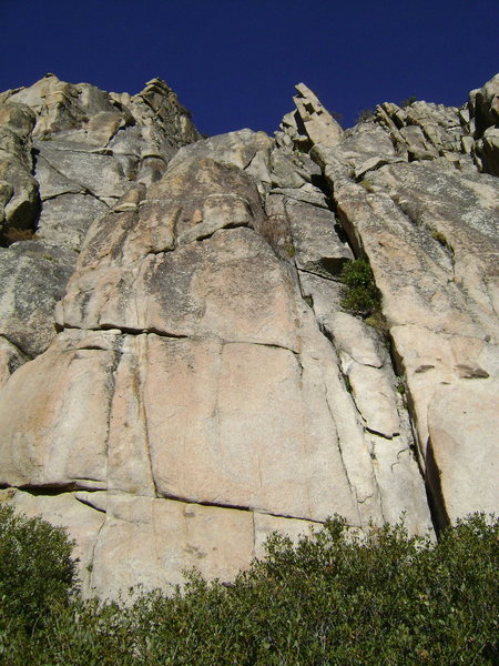 The two first-pitch options for Hand of God which also serve as the approach to Smearing for Jesus (along with several other climbs). The vegetated right crack is 5.8. The blankish looking face on the left is 5.11+ and is marked by a bolt at the start.