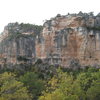 The left end of La Siuranella from near the parking lot, with the Diedre Roig & Diedre Blanc obvious on the right.  A climber (in red) is starting up "L'Escamarla" on the left.