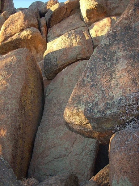 The route starts between large, leaning blocks.  Squeeze through under chockstone with brown tip.