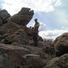 At the top of the original route.  The cedar tree and bolts are a quick scramble over the rocks toward the cross (up canyon). TJ cleans some anchor gear. There is a great rock to wrap a cordolette or webbing around and several cracks for cams or nuts for the anchor.