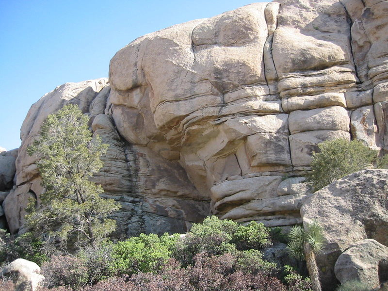 The route goes up the horizontals on the left 5.6 R) , then up a steep crack above (A2+). 