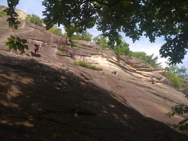 Party of 3 on the second pitch: one person belaying on the far right, one person traversing in the middle, and the third person standing at the top of the first pitch.