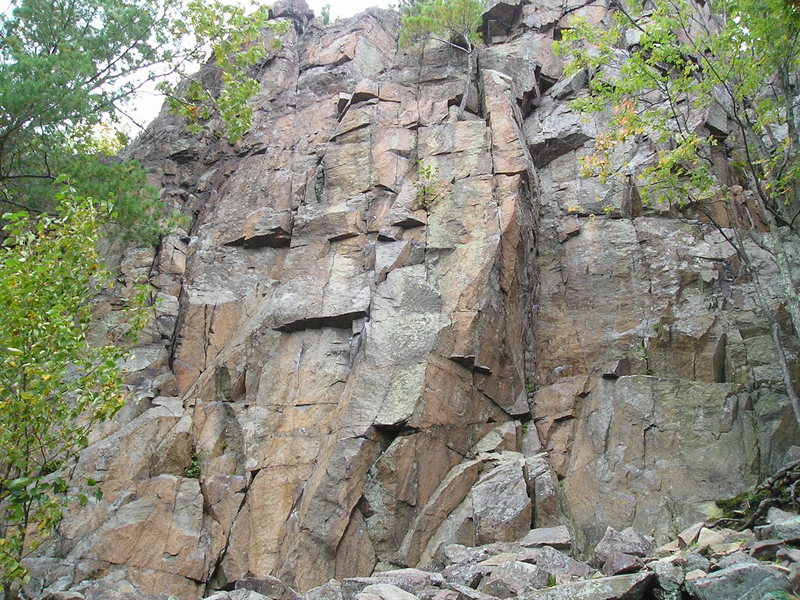 Front of the, Main wall, section. Dihedral route is on right with left sweeping downwards expanding dihedral, Sidewinder can be identified by the small, shadow producing overhang left of the middle of pic, and 40 foot smurf is on the left, just to the right of the leaves.Brulle pour Ciel is on far right going through leaves.