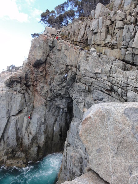 Climbers at rappel anchor, start, traversing overhangs, and top of Beowulf.