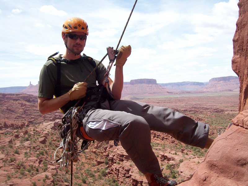 Dustin rappeling down Ancient Art with the Castleton group in the background.