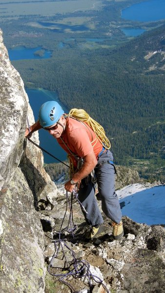 Paul Horton scrambling up the gray ledge to the second rappel station. 