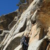 M. Carnes hand drilling the bolt on the ground up first ascent.