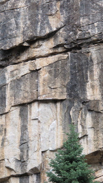 Rasta Man climbs the seam through orange and black rock then move right around the roof.