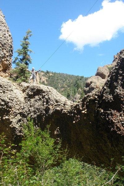 George Bracksieck standing on the higher (west) end of the Natural Arch, Aug 29, 2011. Despite visual competition from the sunlit tree canopies, the dark span of the arch and its lower edge are visible near the bottom of this photo.  I found no cairn or other evidence of previous human visitation anywhere atop the arch.  I left no trace of my visit.