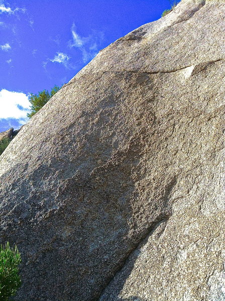 The route starts to the left of the small seam and arches up to the right to a rounded sloper just below the horizontal crack. Then wanders up to the left in a low angle trough to a two bolt anchor on a small ledge.