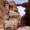 Free-soloing 5.2 on the ancient Bedouin route, North Ridge of Jebel Burdah. The route crosses the arch and continues ont to the summit. Wadi Rum, Jordan, March 2012