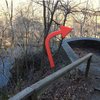 To reach the lower trail:<br>
<br>
Climb over the edge of the "Pedestrian Overlook" and around the front to reach  the river bank.  There is a small gulley with a piece of cordellete installed to help manage the scramble.