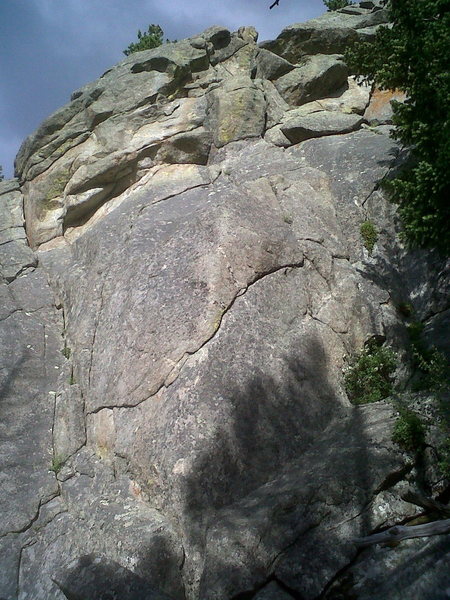 Rock Lobster climbs the indistinct dihedral/gully on the left for 15 feet, then moves right to a bolt by a seam that is followed up and right to a blonde undercling in the upper part of photo. (I'm not talking about the long undercling that goes right and up, across the middle of the photo.) From the right end of the high, short undercling, climb up through a lichen-infested break to the rim. Build an anchor. Walk off.