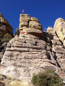 Rupley Tower C.  Pitch 1 of R3 starts at the arrow on the bottom right and ends at the chains indicated by the arrow at the middle left of the frame.  P2 works the cracks up and to the right, and ends up top.  The top arrow and waving gentleman mark the location of the 2-bolt belay station for P2.  Rap off the back side of the tower with another 2-bolt setup up top. 