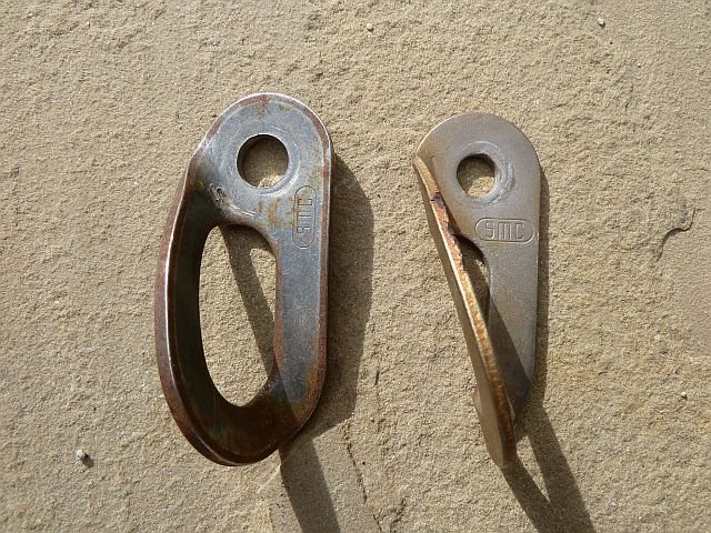 New (left) and old (right) style SMC bolt hangers. 
<br>

<br>
Note the stamp is oriented differently on the two styles.