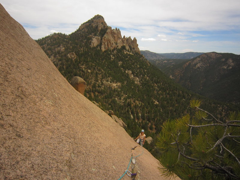 Kat A. following the traverse at the end of P3 on Bishop's Jaggers (5.9) on The Dome in the S. Platte.  The Cynical Pinnacle lies in the background.