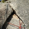 Belay anchor at the top of P2, with Kate heading up P3 to the tree belay, walk-off ledge.