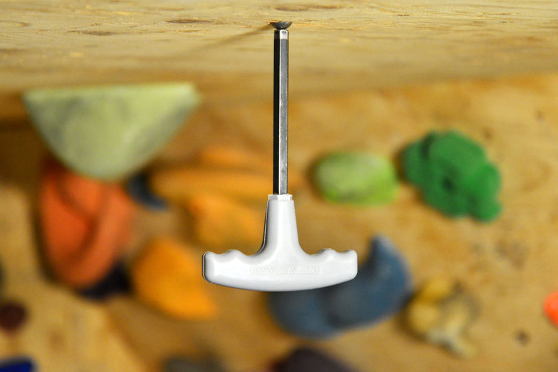allen wrench hanging from a cow magnet on a home rock climbing wall