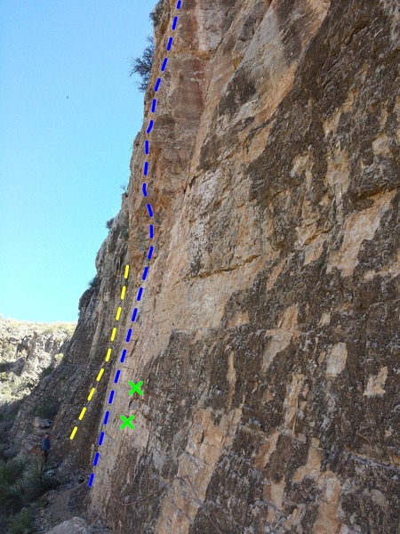 Blue line is approximate route line. Belayer in picture and yellow line are on the climb to the left (unlisted 11d) and two green Xs mark bolts on the climb to the right (unlisted 10b). Looking from the right (South-ish) of the climb.  At the bottom of the photo, you can see the hand-line. Sorry for the crappy picture!