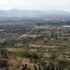 Looking roughly west toward Mexico 130 from the Las Bolas cliff. The obvious paved road is used for access to the crag. The weird housing area mentioned in the approach description can be seen in the left foreground.